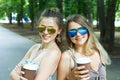 Two beautiful young boho girls have coffee in park