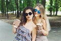 Two beautiful young boho girls have coffee in park