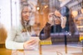 Two Beautiful Women Looking At Phone Together In Cafe Seen Through Window Royalty Free Stock Photo