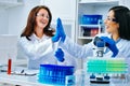 Two beautiful young female scientists working in laboratory and giving high five to each other Royalty Free Stock Photo