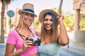 Two beautiful and young girl friends together having fun at the city standing with vintage camera Royalty Free Stock Photo