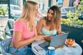 Two beautiful and young girl friends together using computer laptop at cafeteria Royalty Free Stock Photo