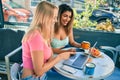 Two beautiful and young girl friends together using computer laptop at cafeteria Royalty Free Stock Photo