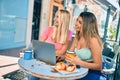 Two beautiful and young girl friends together using computer laptop at cafeteria Royalty Free Stock Photo