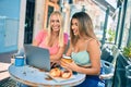 Two beautiful and young girl friends together using computer laptop at cafeteria Royalty Free Stock Photo