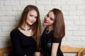 Two beautiful young girls in black dresses sit on the bench and gossip Royalty Free Stock Photo