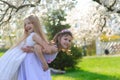 Beautiful young girls with blue eyes in a white dresses in the garden with apple trees blosoming having fun and enjoying smell of Royalty Free Stock Photo