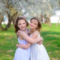 Beautiful young girls with blue eyes in a white dresses in the garden with apple trees blosoming having fun and enjoying smell of Royalty Free Stock Photo