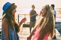 Two beautiful young girls having fun at the evening seaside with group of their friends on background Royalty Free Stock Photo