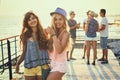 Two beautiful young girls having fun at the evening seaside with group of their friends on background toned in vintage Royalty Free Stock Photo