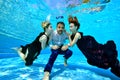 Two beautiful young girls with red and white hair swim and play with a young man in a white shirt underwater at the bottom of the Royalty Free Stock Photo