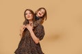 Two beautiful young girls sisters in nice animal pattern dresses with straw hats posing in studio Royalty Free Stock Photo