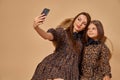 Two beautiful young girls sisters take selfies in nice animal pattern dresses with straw hats posing in studio Royalty Free Stock Photo