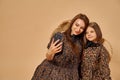 Two beautiful young girls sisters take selfies in nice animal pattern dresses with straw hats posing in studio Royalty Free Stock Photo