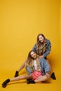 Two beautiful young twins women with slim perfect bodies in denim jackets and pink shorts, posing at the yellow Royalty Free Stock Photo