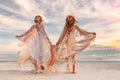 Two beautiful young woman in elegant boho dresses outdoors at sunset Royalty Free Stock Photo