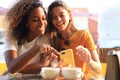 Two beautiful young woman sitting at cafe drinking coffee and looking at mobile phone Royalty Free Stock Photo