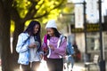 Two beautiful young woman using mobile phone in the street. Royalty Free Stock Photo