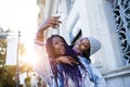 Two beautiful young woman using mobile phone in the street. Royalty Free Stock Photo