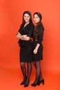 Two beautiful young women in business suits on a red background Royalty Free Stock Photo