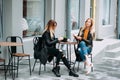 Two beautiful young women drinking tea and gossiping in nice restaurant outdoor . Royalty Free Stock Photo