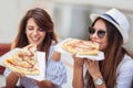 Two beautiful young women eating pizza after shopping Royalty Free Stock Photo