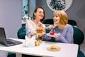 Two beautiful young women enjoying coffee and cake together in a cafe sitting at a table laughing and gossiping with Royalty Free Stock Photo