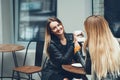 Two beautiful young women in fashion clothes having rest talking and drinking coffee in restaurant outdoor. Royalty Free Stock Photo