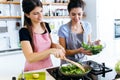 Two beautiful young women frying chards into the pan. Royalty Free Stock Photo