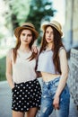 Two beautiful young women in hats having fun in the city. Warm summer. Girls in sunglasses.
