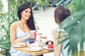 Two beautiful young women are having coffee and desserts together at outdoors cafe. Royalty Free Stock Photo