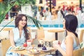 Two beautiful young women are having coffee and desserts together at outdoors cafe. Royalty Free Stock Photo