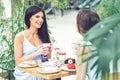 Two beautiful young women are having coffee and desserts together at outdoors cafe Royalty Free Stock Photo