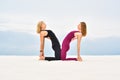 Two beautiful young women performing yoga pose ushtrasana together