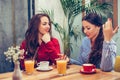 Two beautiful young women sitting in a cafe, drinking coffee and having a pleasant conversation Royalty Free Stock Photo