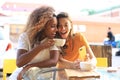 Two beautiful young woman sitting at cafe drinking coffee and looking at mobile phone Royalty Free Stock Photo