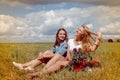 Two beautiful young women sitting on summer meadow Royalty Free Stock Photo