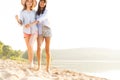 Two beautiful young women strolling on a beach. Female friends walking on the beach and laughing on a summer day. Royalty Free Stock Photo