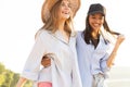 Two beautiful young women strolling on a beach. Female friends walking on the beach and laughing on a summer day. Royalty Free Stock Photo