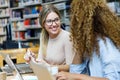 Two beautiful young women studying in a university library. Royalty Free Stock Photo