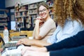 Two beautiful young women studying in a university library.