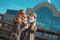 Two beautiful young women talking while walking the street after shopping holding the coffee and smiling. Royalty Free Stock Photo