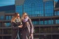 Two beautiful young women talking while walking the street after shopping holding the coffee and smiling. The weather is great Royalty Free Stock Photo