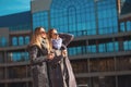 Two beautiful young women talking while walking the street after shopping holding the coffee and smiling. The weather is great tod Royalty Free Stock Photo