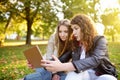 Two beautiful young women using tablet computer together at sunny park. Remote communication. Dating site