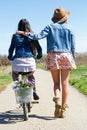 Two beautiful young women with a vintage bike in the field. Royalty Free Stock Photo