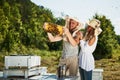 Two beekeepers works with honeycomb full of bees outdoors at sunny day. Man and woman Royalty Free Stock Photo