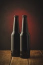 two beer bottles a dark background with red light/two beer bottles a dark background with red light. Selective focus Royalty Free Stock Photo