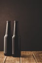 two beer bottles on a wooden table against a dark background/ two beer bottles on a wooden table against a dark background, Royalty Free Stock Photo