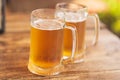 Two beer mugs closeup on wooden natural table.Two glass beer on wood background Royalty Free Stock Photo